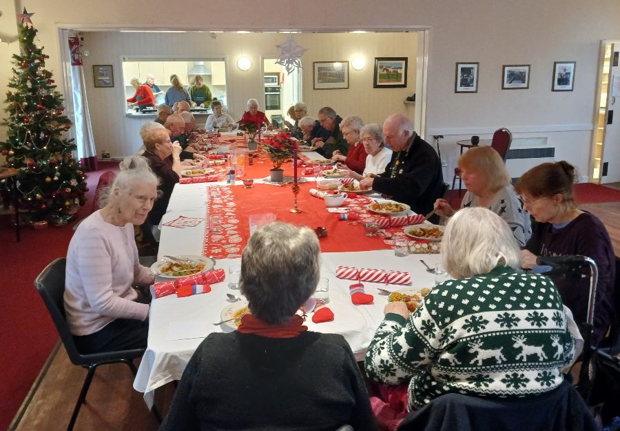 Elderly people sitting at a christmas lunch table